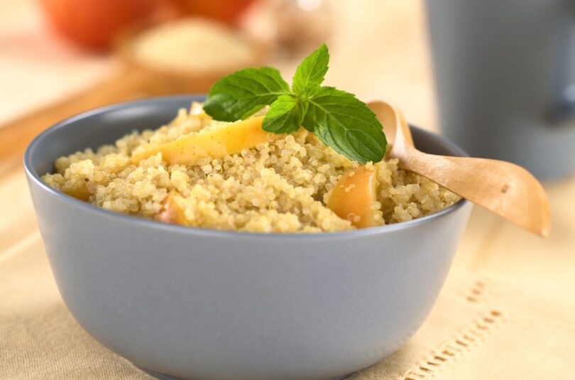 Cremige Quinoa Bowl garniert mit Apfelstücken, Kürbiskernen und Mandelbutter