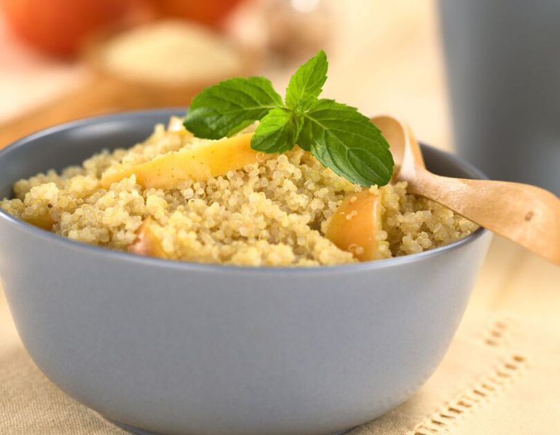 Cremige Quinoa Bowl garniert mit Apfelstücken, Kürbiskernen und Mandelbutter