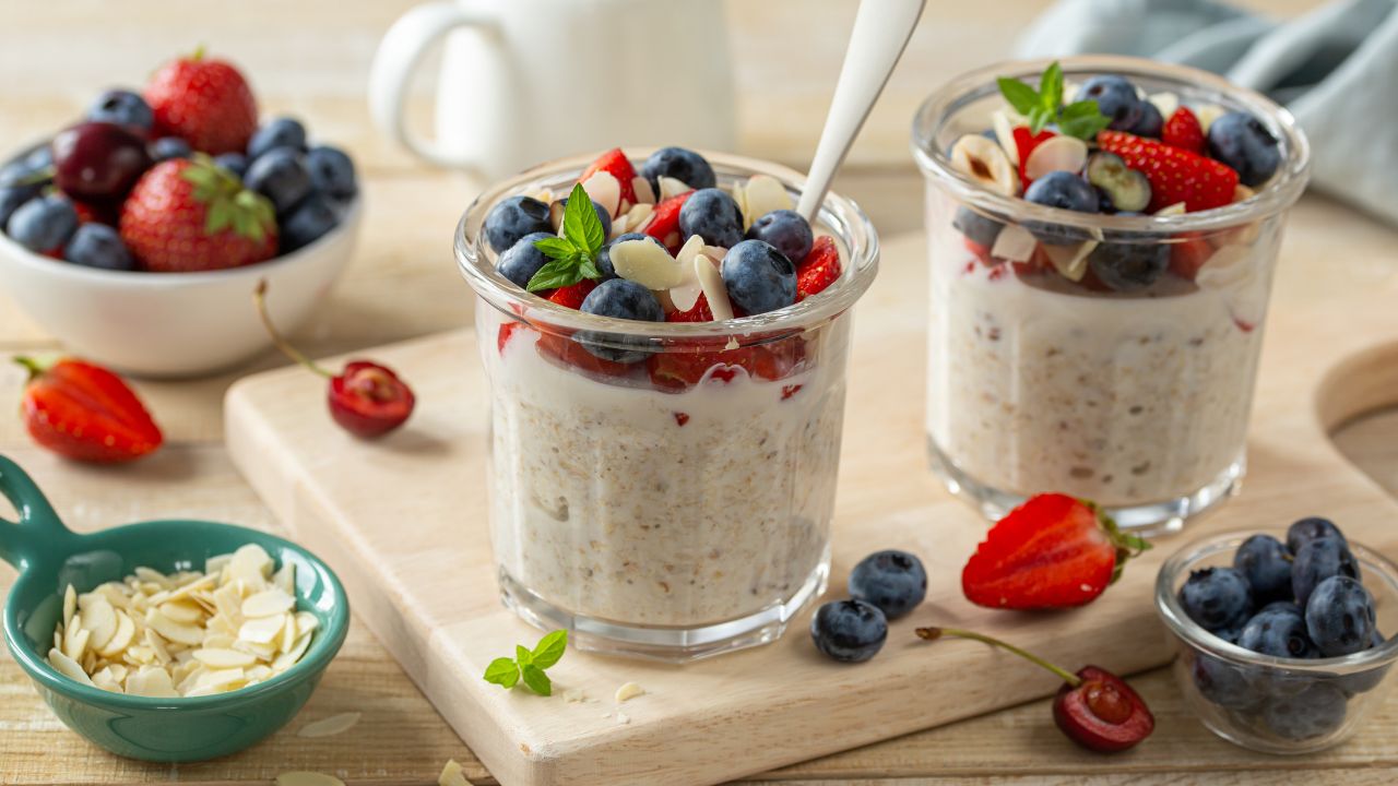 Overnight Oats in einem Glas serviert mit frischen Beeren und Mandeln Description: Cremige Overnight Oats mit frischen Beeren, Chiasamen und gehackten Mandeln in einem Glas angerichtet