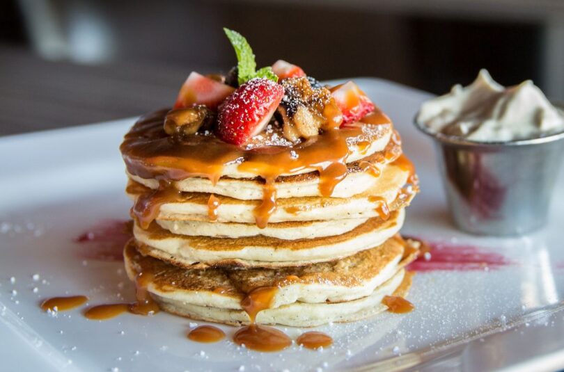 Stapel goldbrauner, fluffiger Buttermilch Pancakes mit Ahornsirup und frischen Beeren