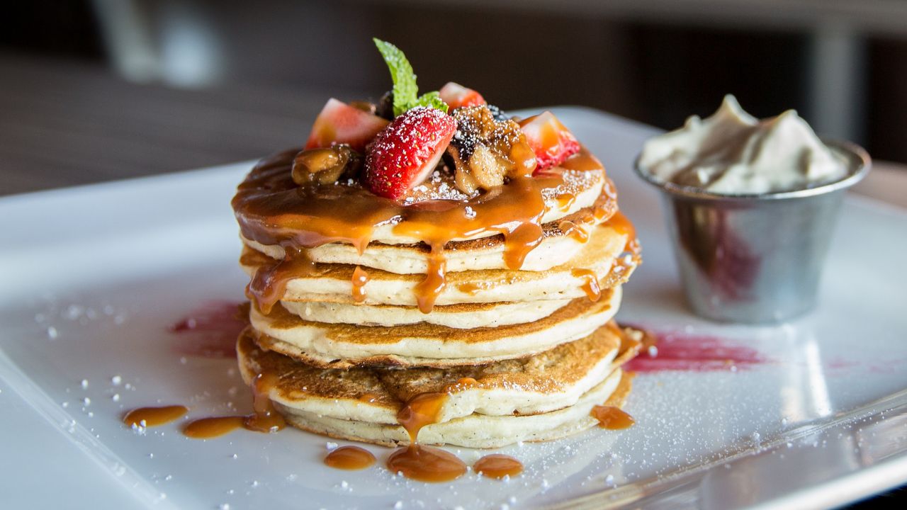 Stapel goldbrauner, fluffiger Buttermilch Pancakes mit Ahornsirup und frischen Beeren